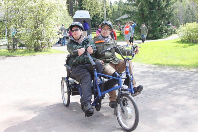 Kilpailujen oheispisteellä pääsi kokeilemaan vierekkäin poljettavaa polkupyörää. Kuvassa pyöräilevät Mikko Vuorinen ja hänen avustajansa Oskari Martti.